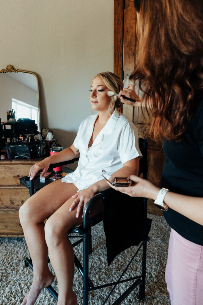 Bride getting her make up done at her Airbnb elopement in Bailey, Colorado