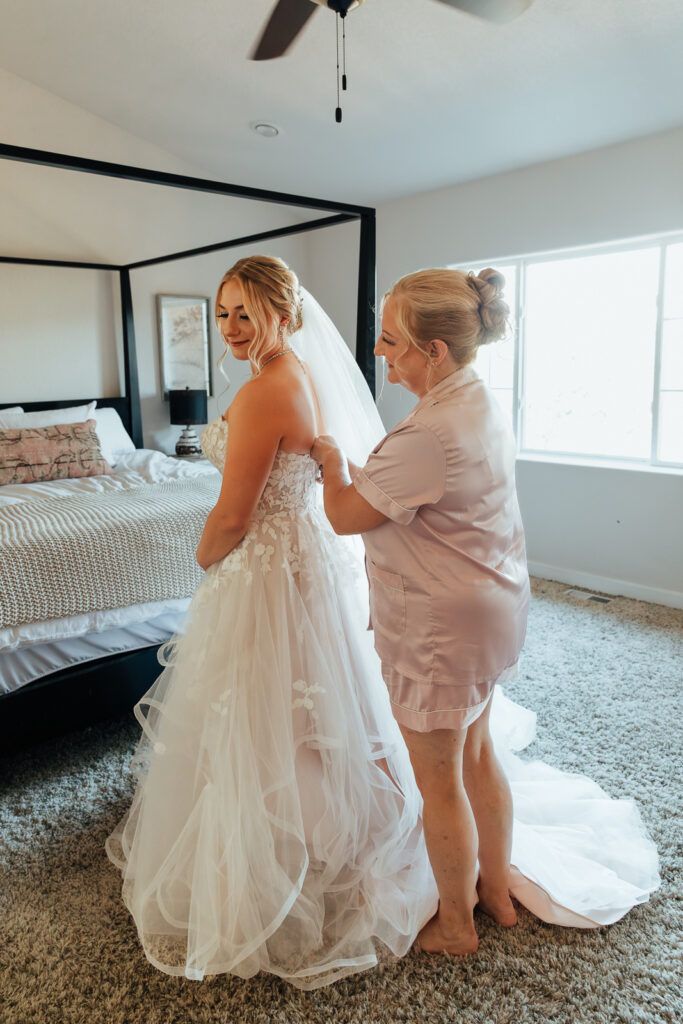 Bride's mom helping her into her dress at an Airbnb elopement in Bailey, Colorado
