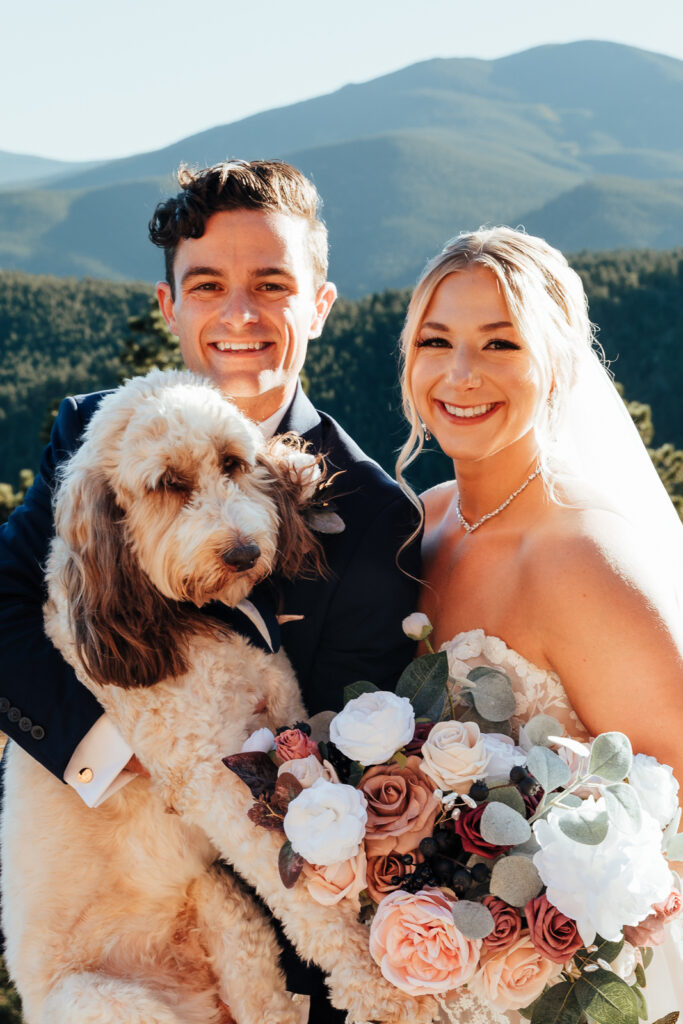 A couple smiling while holding their dog at their Airbnb elopement in Bailey, Colorado