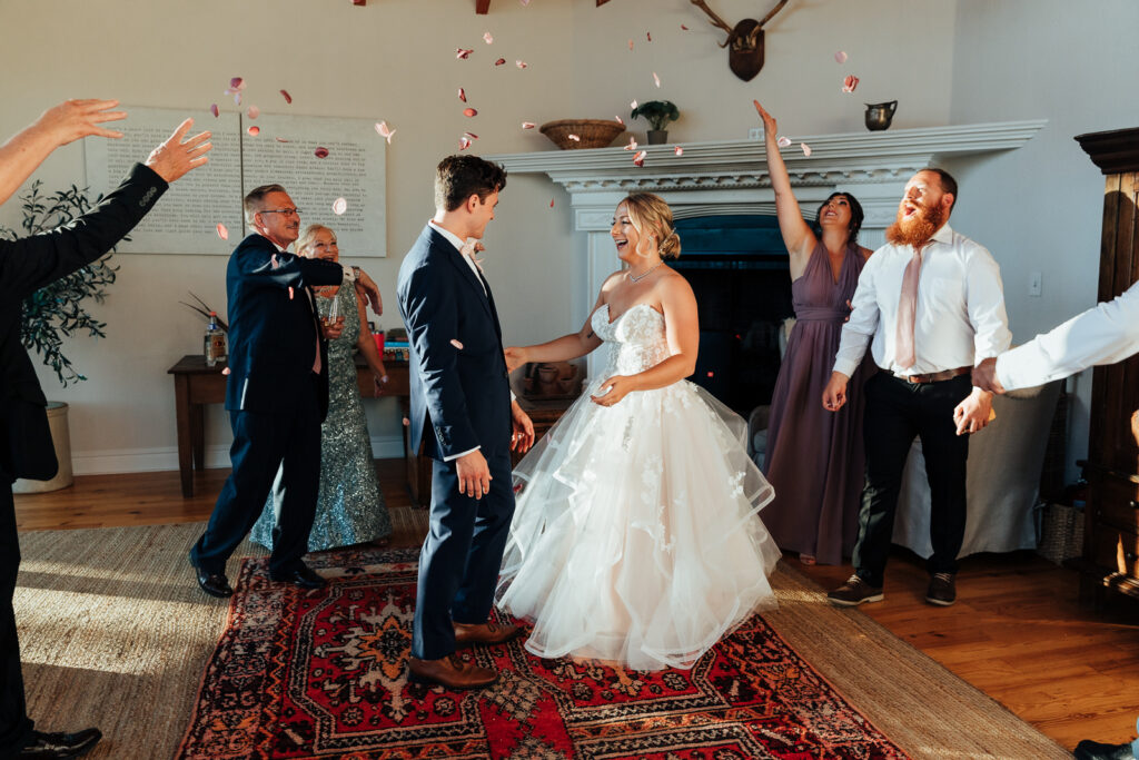 Couple's family throwing flower petals over them as they finish their first dance at their Airbnb elopement in Bailey, Colorado
