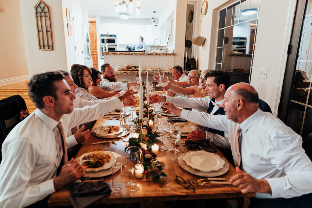 Couple and their family toasting at dinner at their Airbnb elopement in Bailey, Colorado