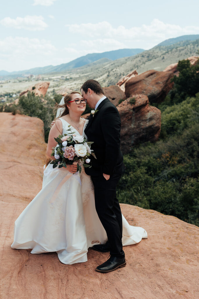 Husband kissing his wife on the cheek at their elopement at Red Rocks Amphitheater near Denver