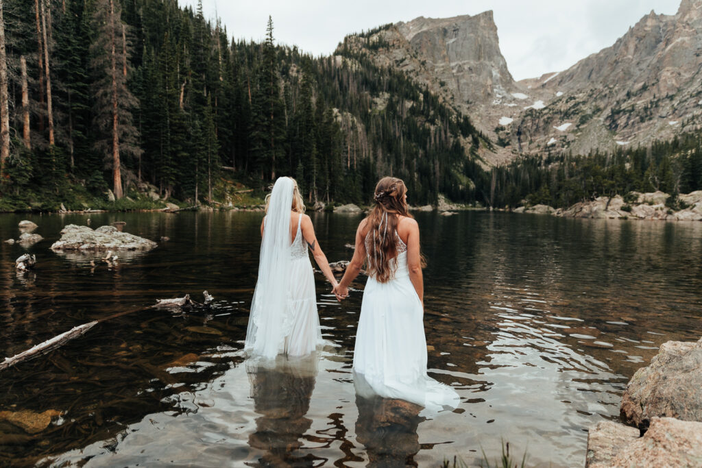 Couple holding hands while standing in Dream Lake, Rocky Mountain National Park in Estes Park