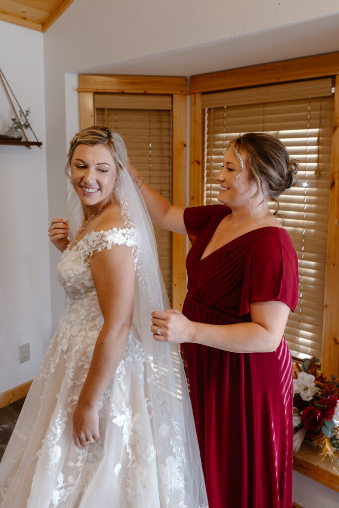 Bride's sister helping her put her veil while getting ready at their Airbnb